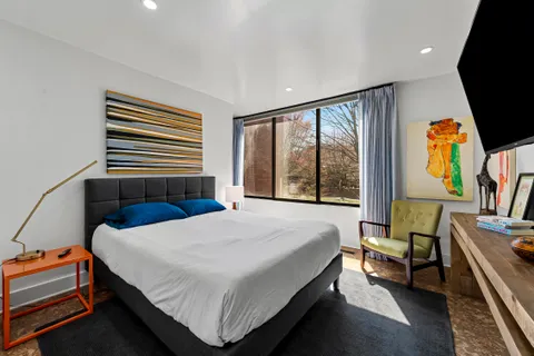 a bedroom with a bed a flat screen tv and a window
