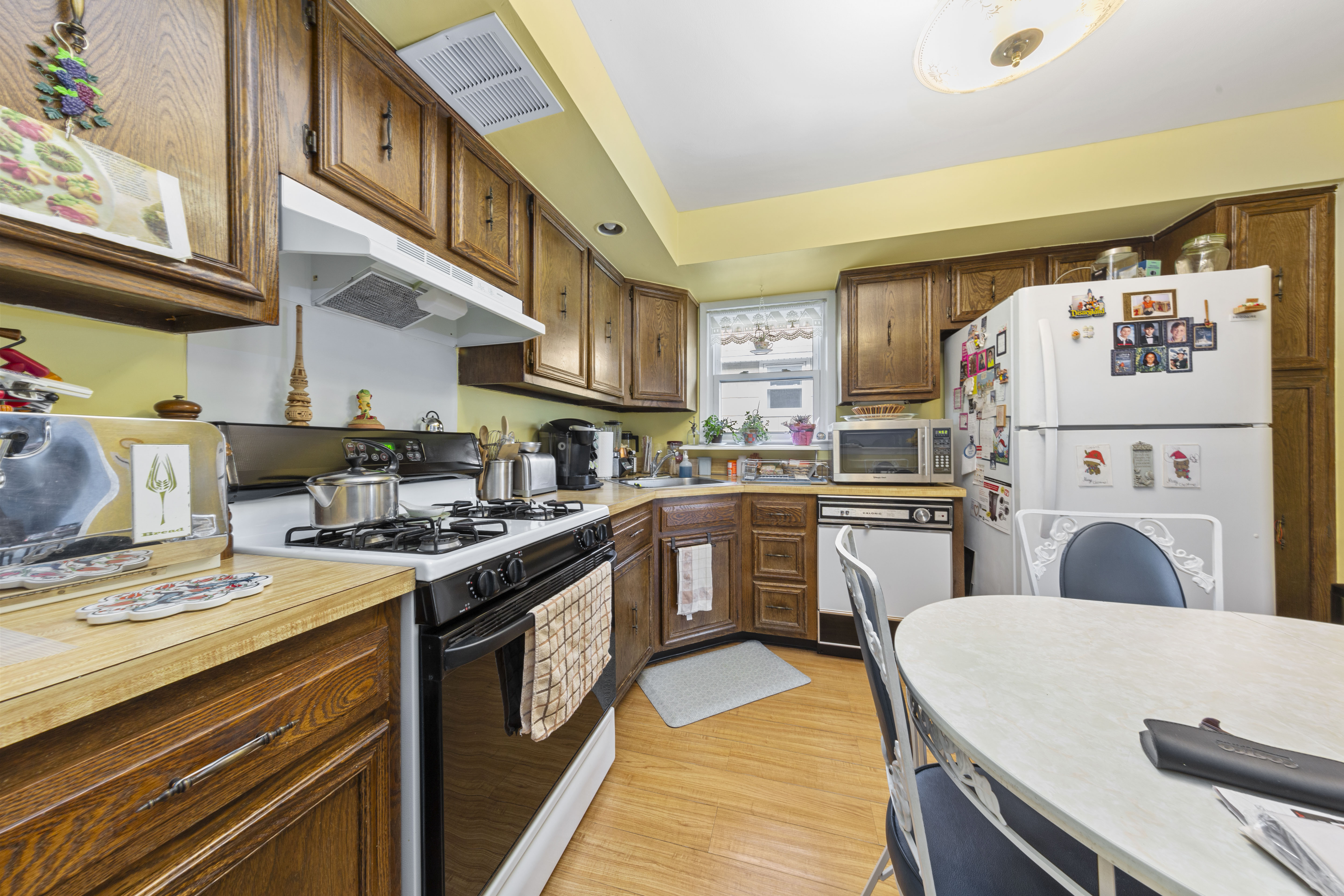 240-47 68th Avenue Queens, NY 11362 - Photo 21 of 39 a kitchen with kitchen island a stove a sink dishwasher and white refrigerator with cabinets