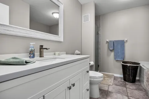 a bathroom with a granite countertop sink a toilet and a mirror