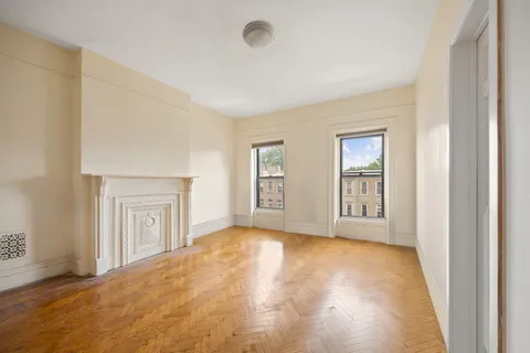 a view of an empty room with window and wooden floor