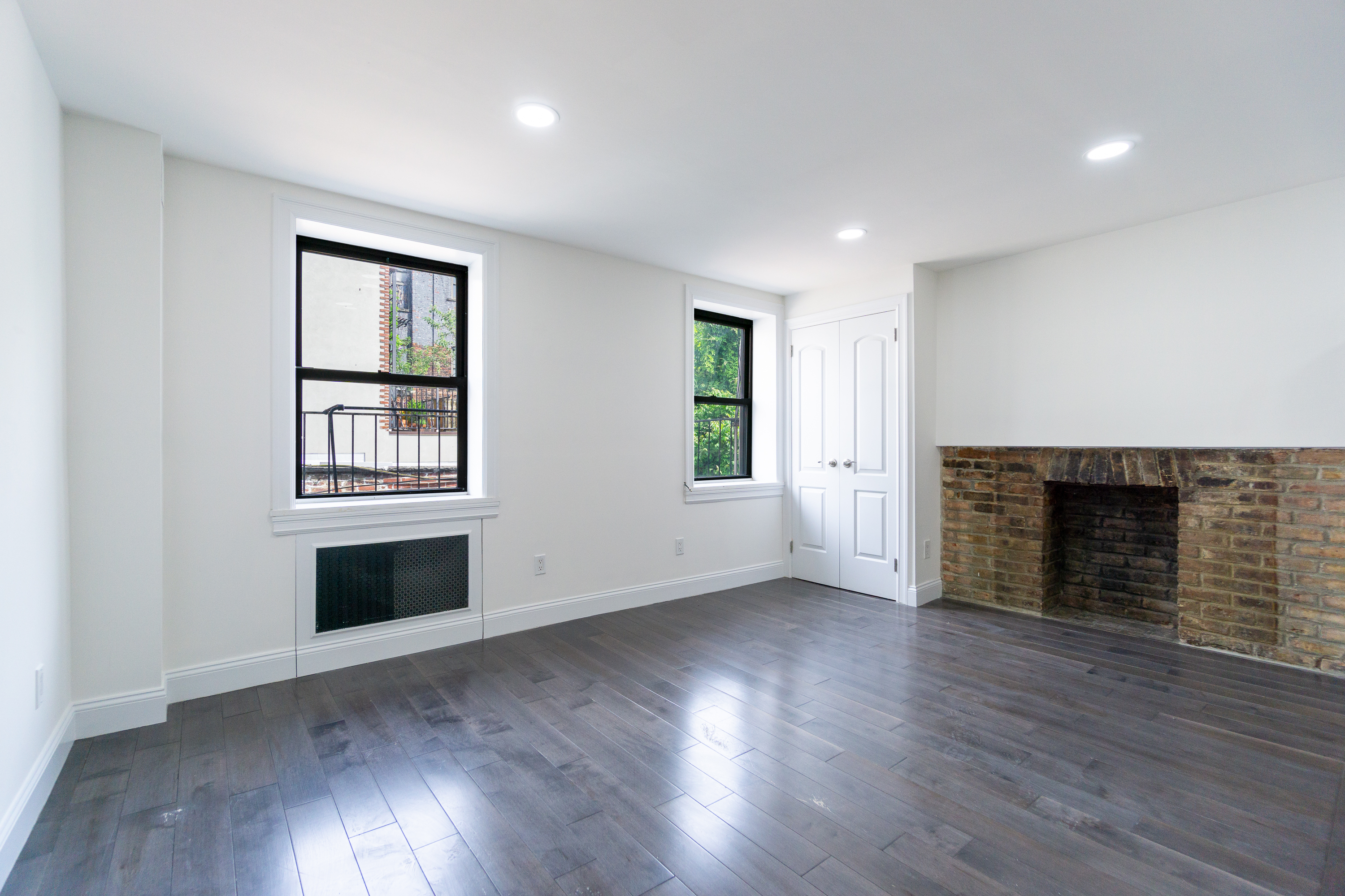 400 East 9th Street, Unit 4D Manhattan, NY 10009 - Photo 2 of 13 an empty room with wooden floor fireplace and windows