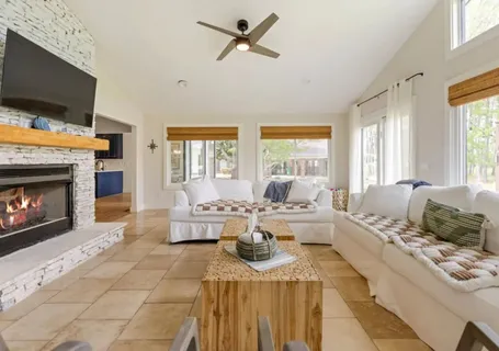 a living room with a table a dining table with wooden floor potted plant and windows