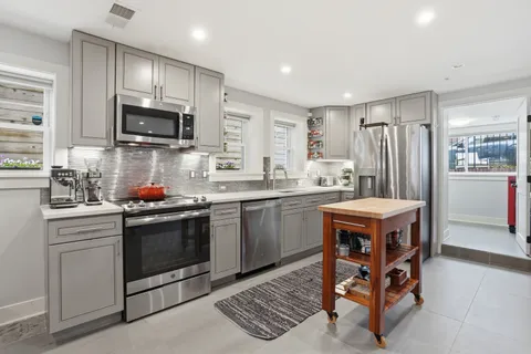 a kitchen with stainless steel appliances a stove a sink a microwave a refrigerator and cabinets