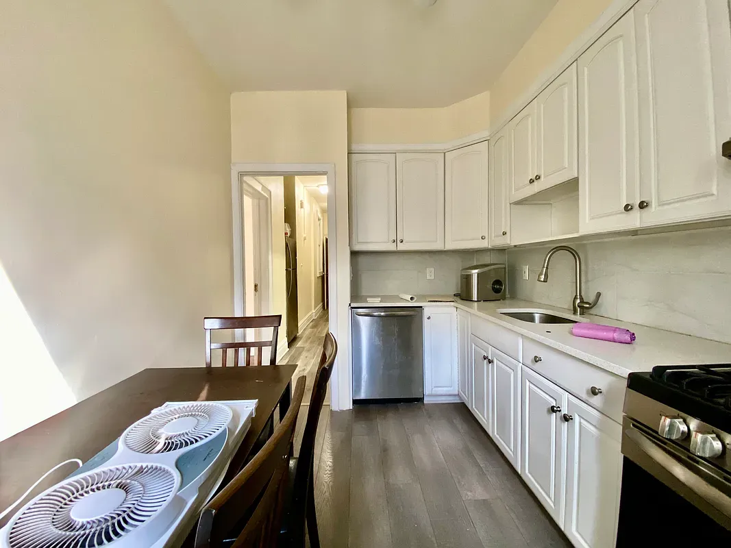 a kitchen with a stove a sink a refrigerator cabinets and dining table