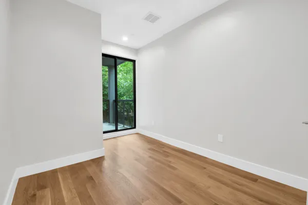 a view of an empty room with wooden floor and a window