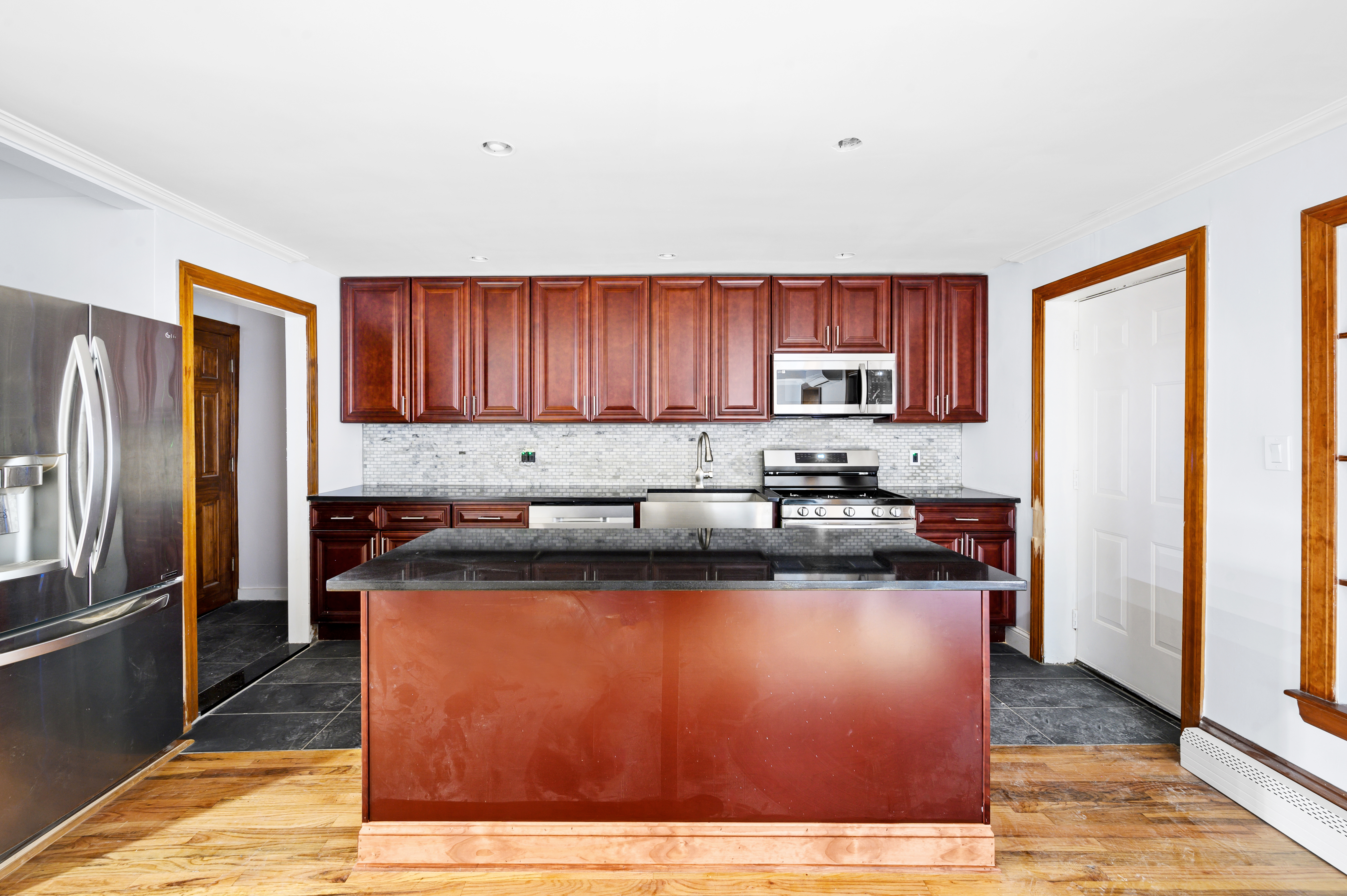 a kitchen with stainless steel appliances granite countertop a refrigerator stove and a sink with wooden floor