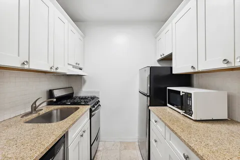 a kitchen with granite countertop white cabinets and stainless steel appliances