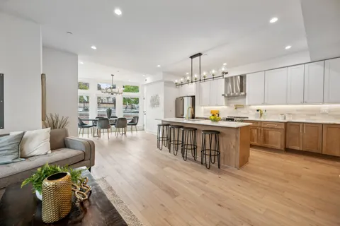 a kitchen with stainless steel appliances kitchen island granite countertop a stove a sink a dining table and chairs