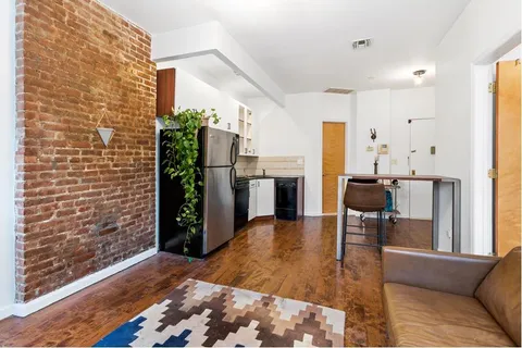 a living room with furniture a refrigerator and kitchen view
