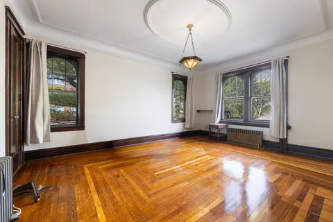 a view of an empty room with window wooden floor and front door