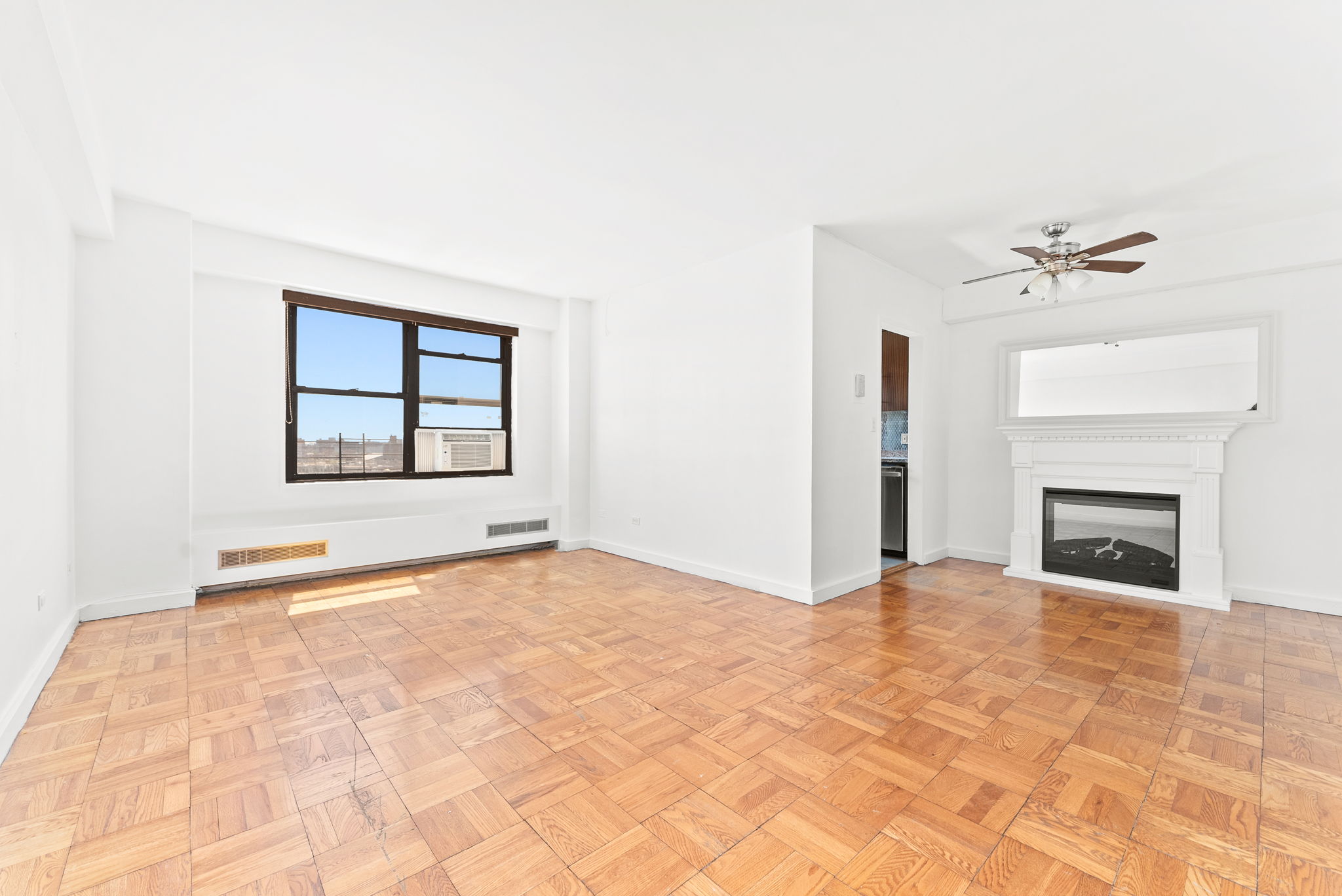 a view of an empty room with a fireplace and a window