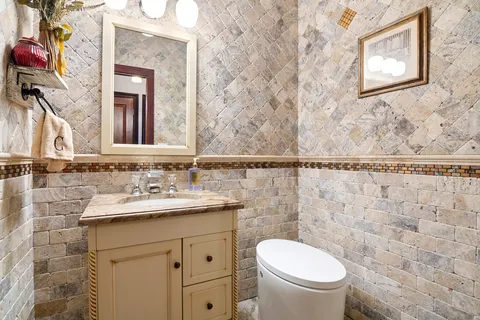 a bathroom with a granite countertop toilet sink and mirror
