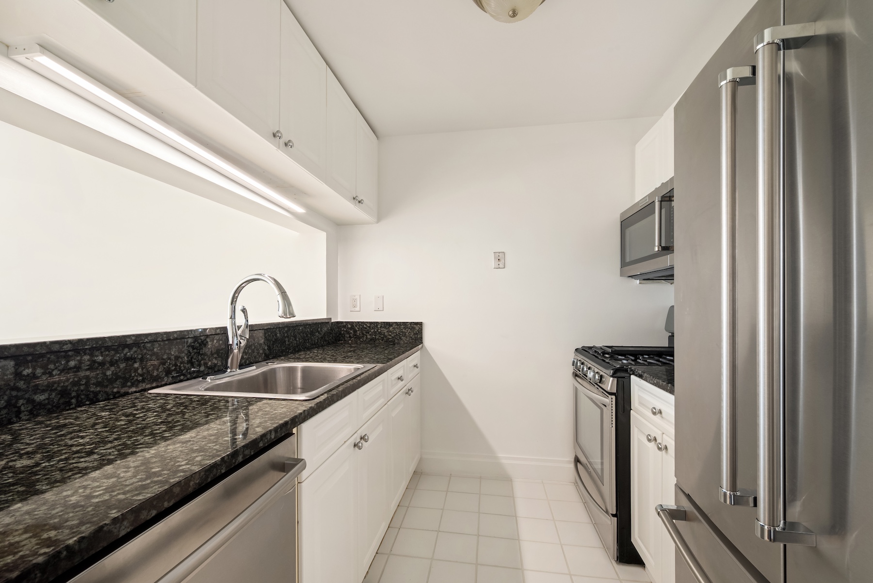 404 East 76th Street, Unit 7C Manhattan, NY 10021 - Photo 5 of 13 a kitchen with stainless steel appliances granite countertop a sink stove and refrigerator
