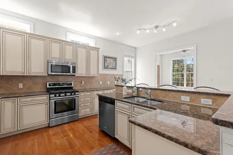 a kitchen with granite countertop a sink a stove top oven and cabinetry