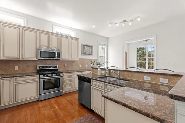 a kitchen with granite countertop a sink a stove top oven and cabinetry