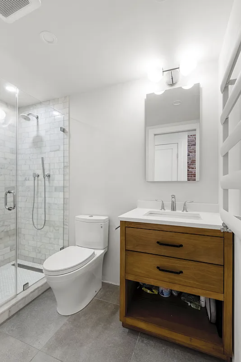 169 Putnam Avenue, Unit 2 Brooklyn, NY 11216 - Photo 6 of 10 a bathroom with a toilet a sink a mirror and a shower