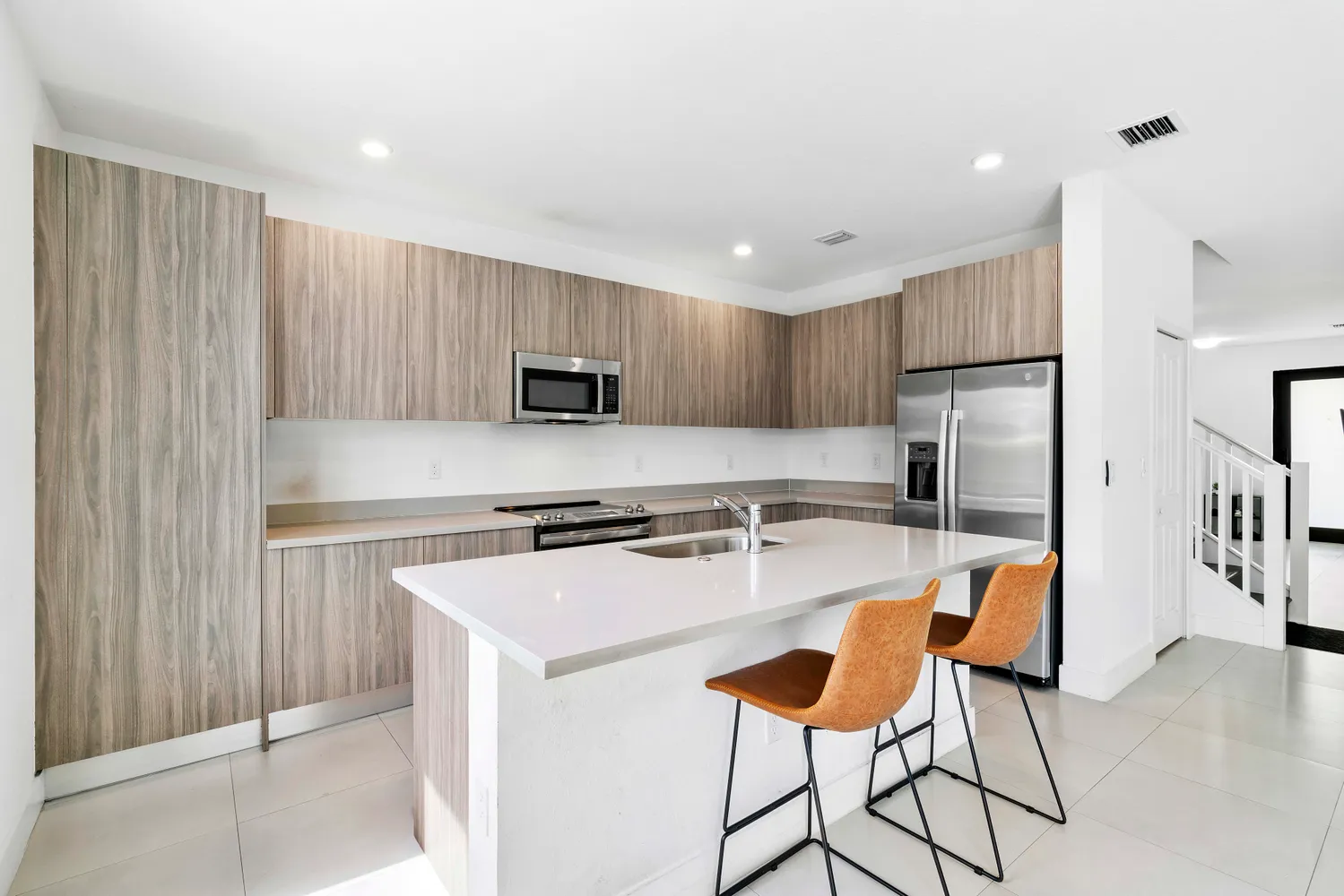 a kitchen with stainless steel appliances granite countertop a refrigerator a stove a sink dishwasher and white cabinets with wooden floor