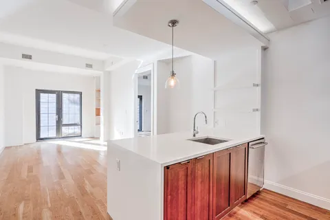 a hallway with a sink a window and wooden floor