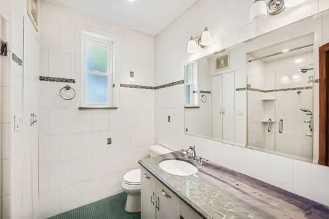 a bathroom with a granite countertop sink toilet a large mirror and shower