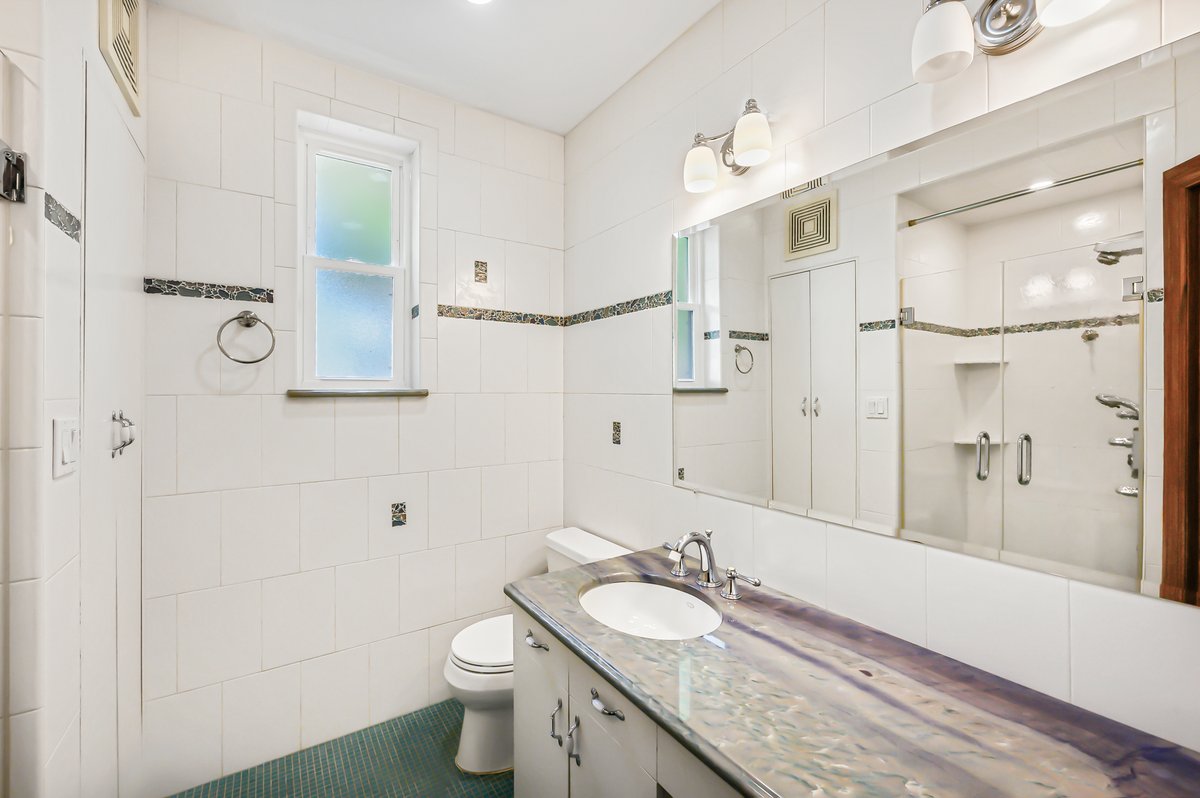 1702 11th Avenue Brooklyn, NY 11218 - Photo 17 of 25 a bathroom with a granite countertop sink toilet a large mirror and shower