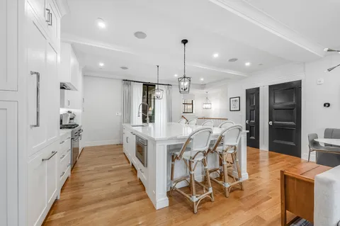 a large white kitchen with lots of counter space dining table and stainless steel appliances