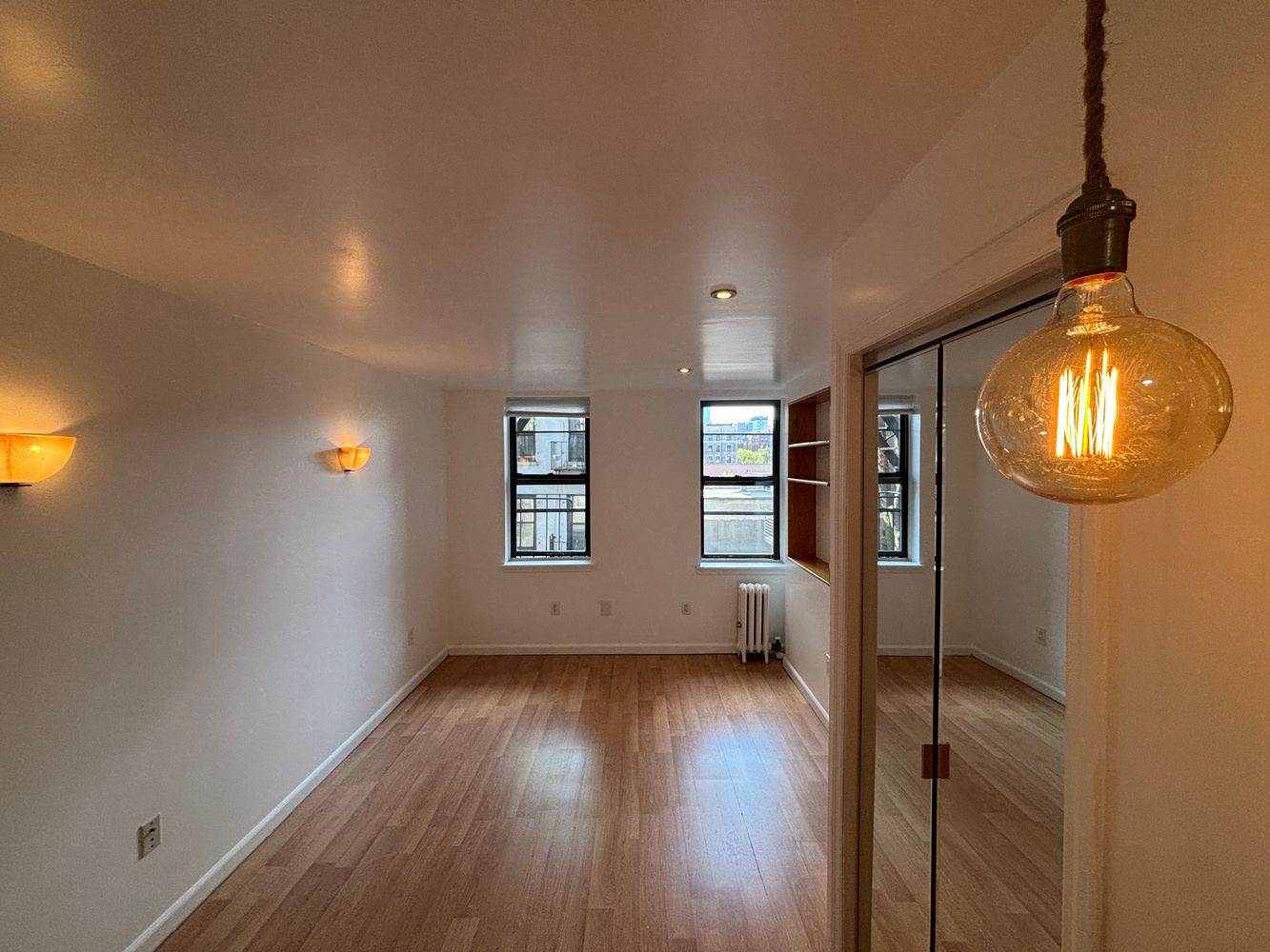 an empty room with wooden floor and windows