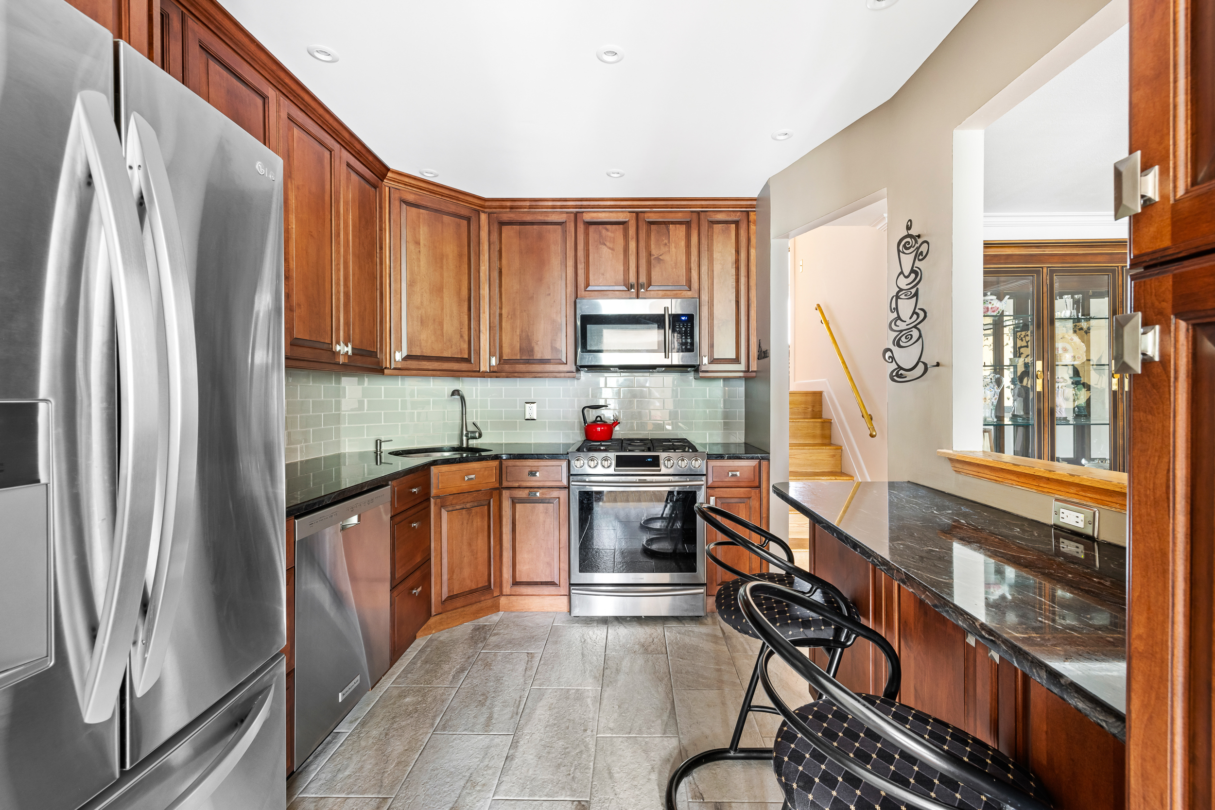 a kitchen with stainless steel appliances granite countertop a refrigerator a stove and a sink with wooden floor