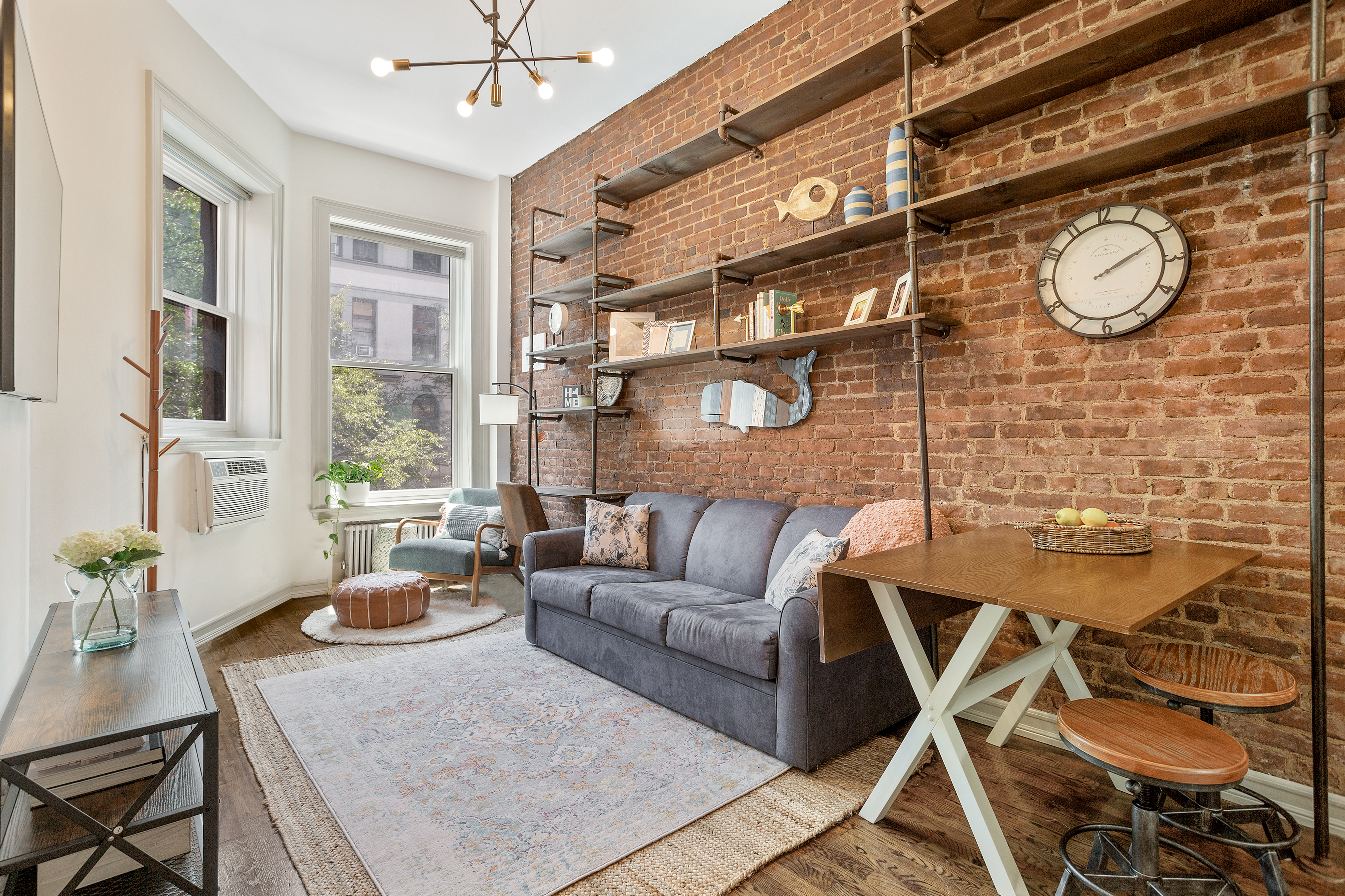 a living room with couches a fireplace and a large window with wooden floor