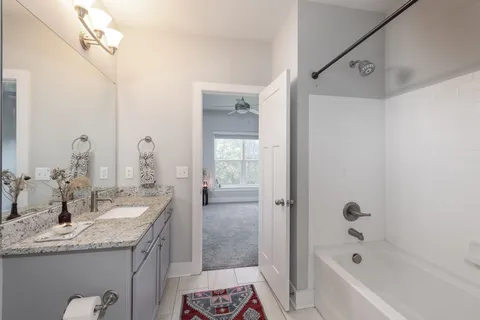 a bathroom with a granite countertop sink a mirror a bathtub and shower
