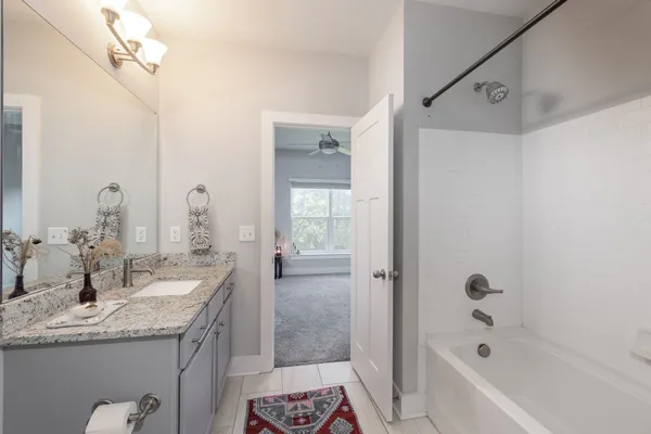 a bathroom with a granite countertop sink a mirror a bathtub and shower