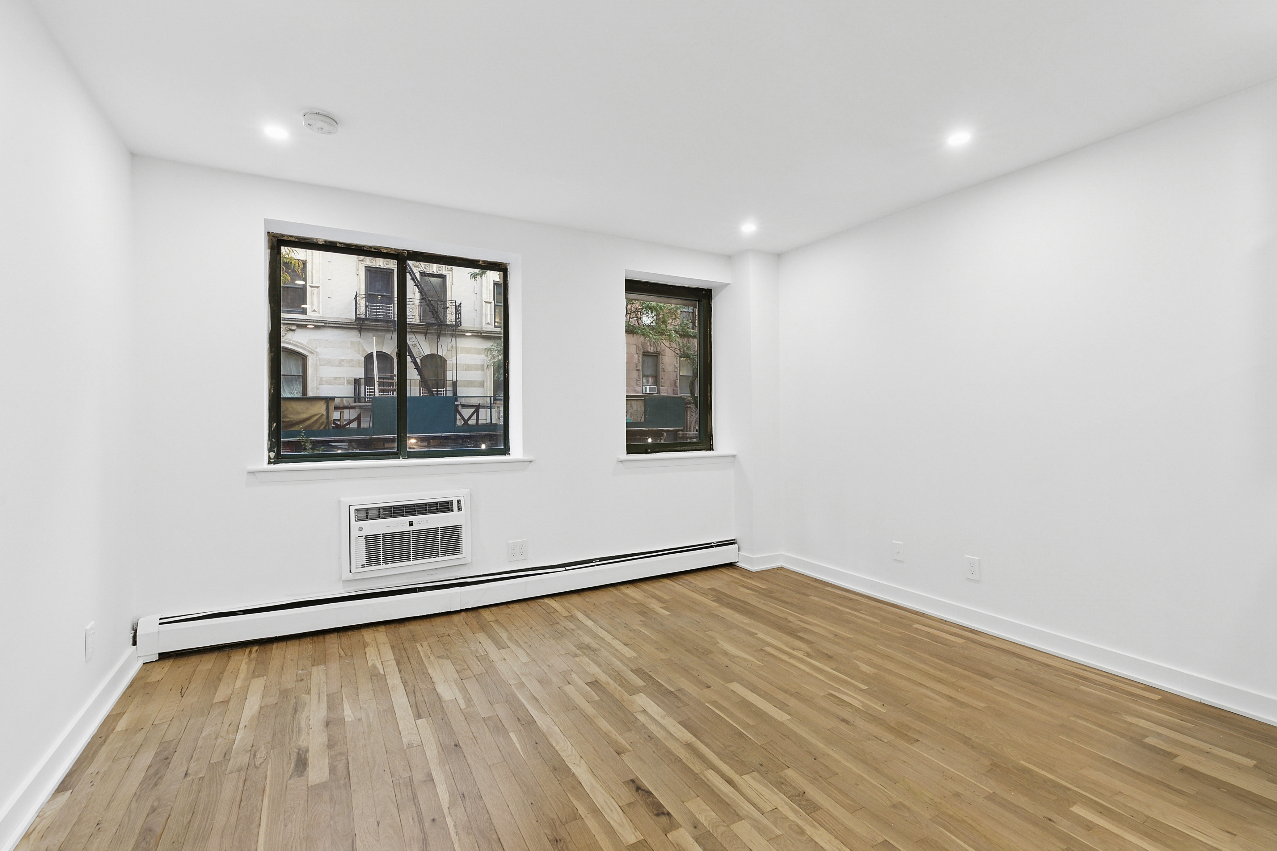 an empty room with wooden floor and windows