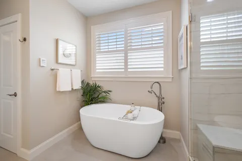 a white bath tub sitting in a bathroom next to a window