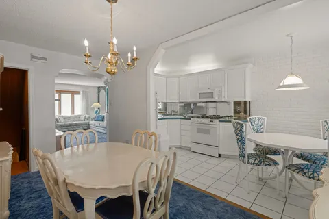 a kitchen with stainless steel appliances granite countertop a dining table chairs refrigerator and microwave