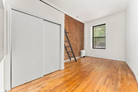 a view of an empty room with a window and wooden floor