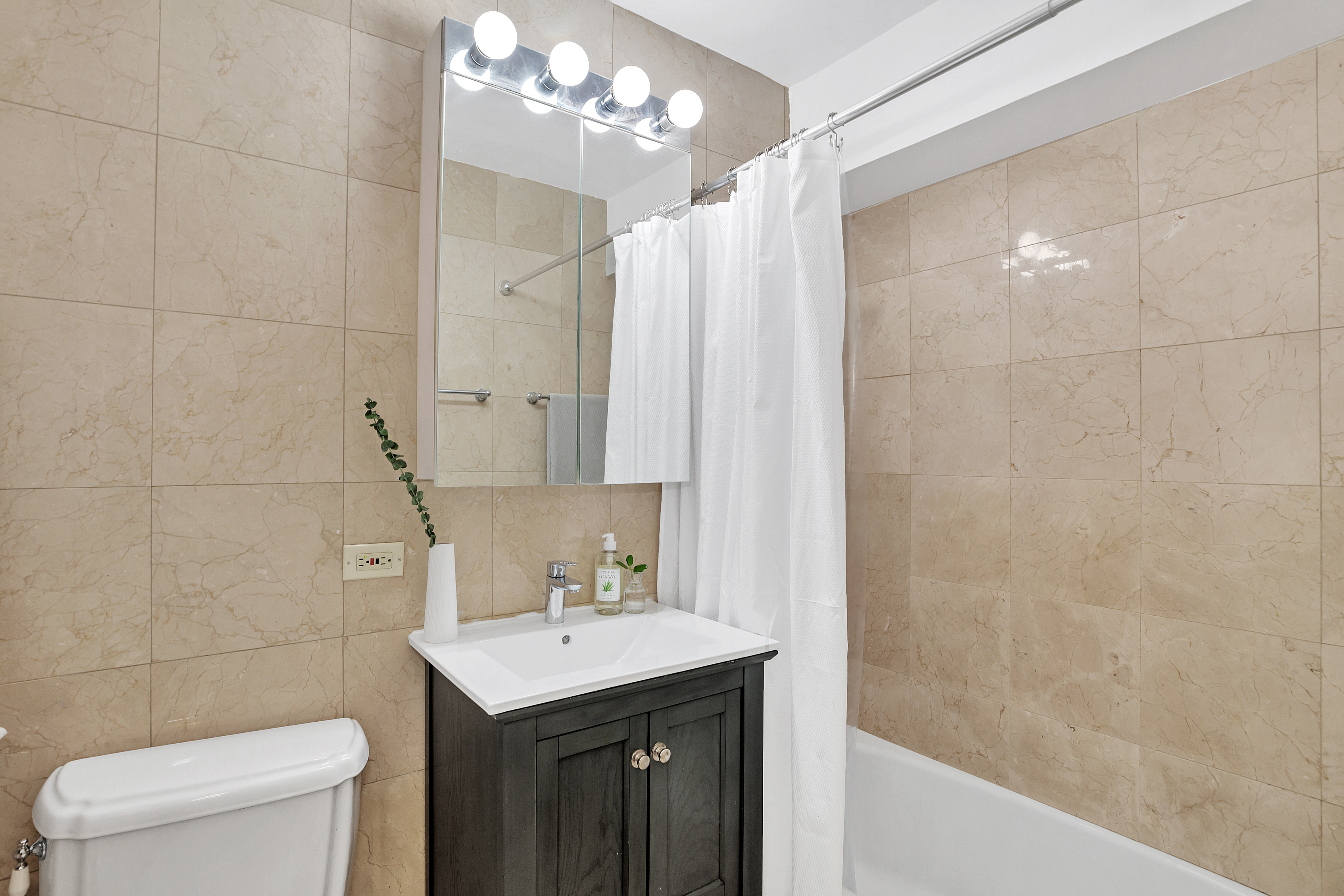 166 East 61st Street, Unit 16G Manhattan, NY 10065 - Photo 5 of 6 a bathroom with a sink a toilet and shower