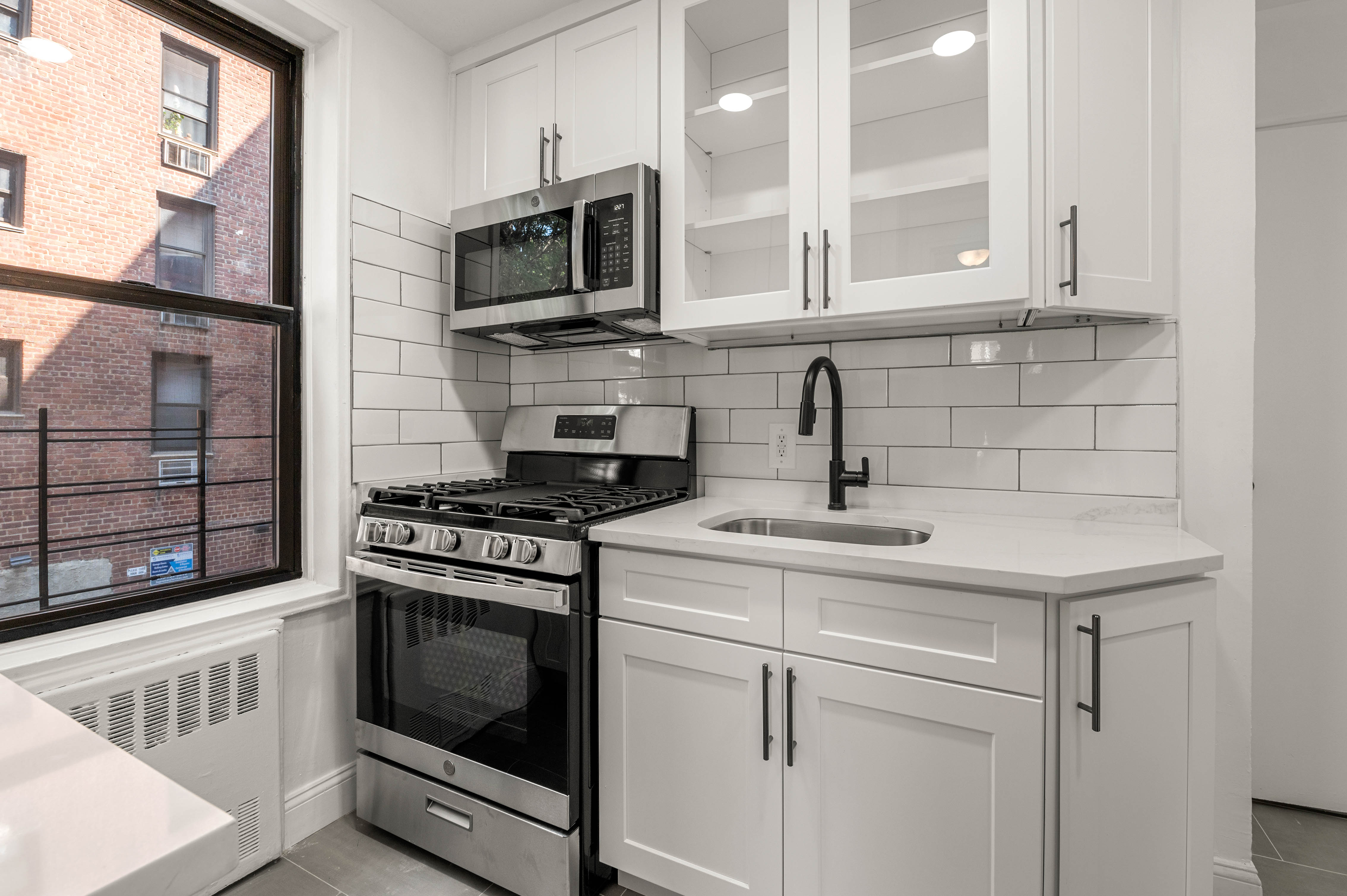 65-15 38th Avenue, Unit 1G Queens, NY 11377 - Photo 5 of 12 a kitchen with stainless steel appliances granite countertop a sink and a stove