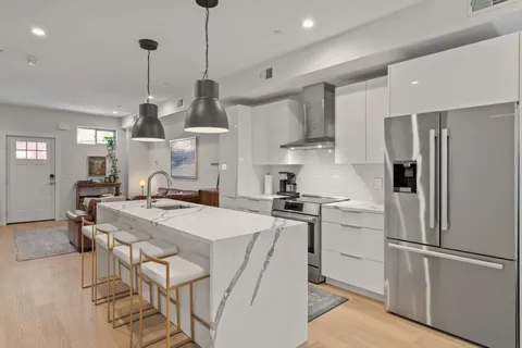 a kitchen with stainless steel appliances granite countertop a refrigerator a sink dishwasher a stove and white cabinets with wooden floor