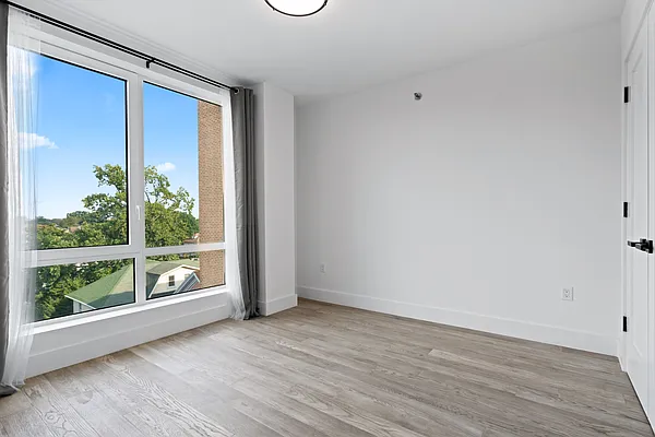 1673 Ocean Avenue, Unit PH4 Brooklyn, NY 11230 - Photo 4 of 13 a view of an empty room with wooden floor and a window