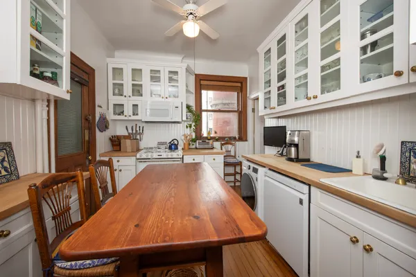 a kitchen with stainless steel appliances granite countertop a table chairs in it and wooden floors