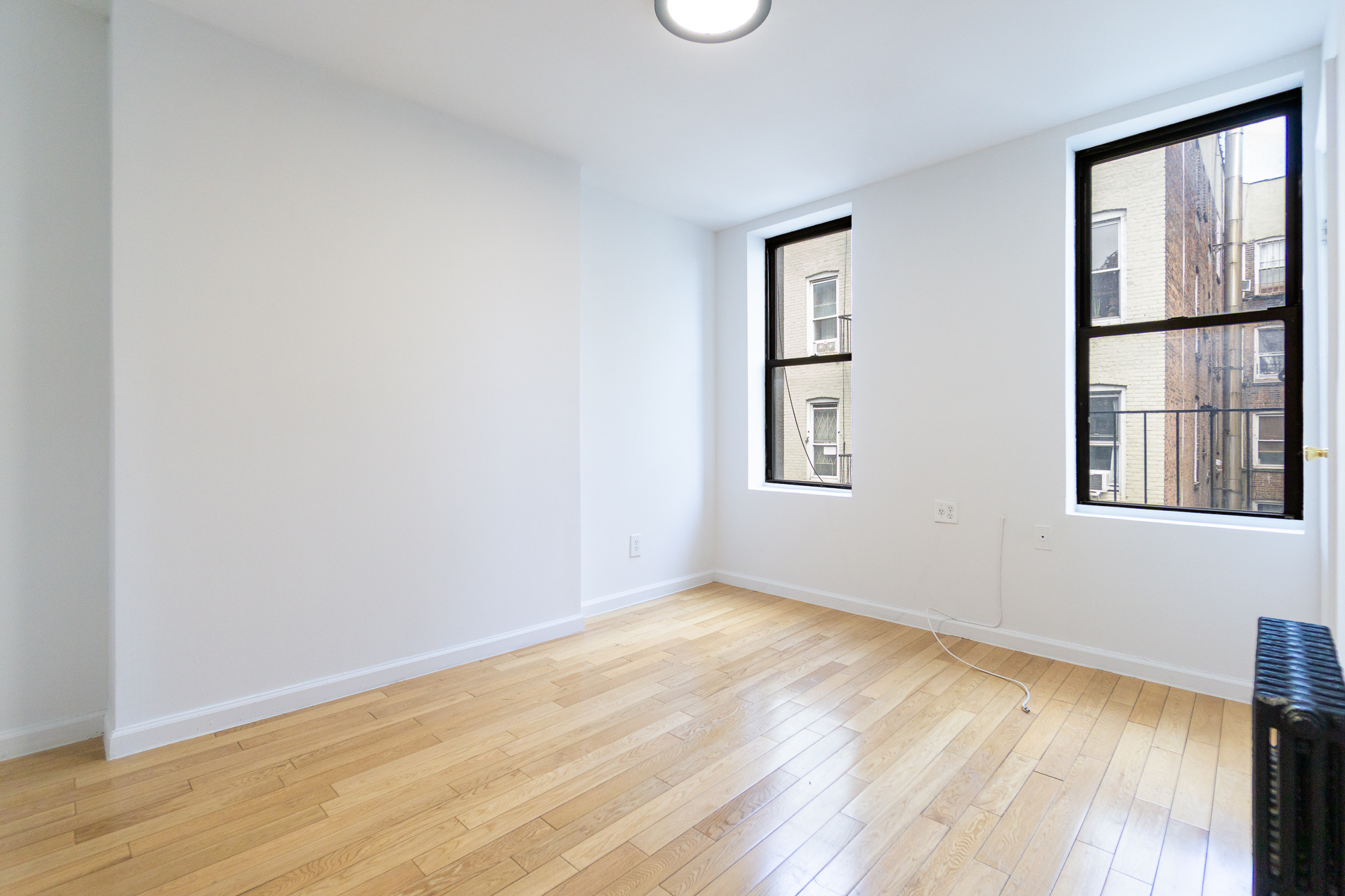 337 East 6th Street, Unit 9 Manhattan, NY 10003 - Photo 2 of 15 a view of an empty room with wooden floor and a window