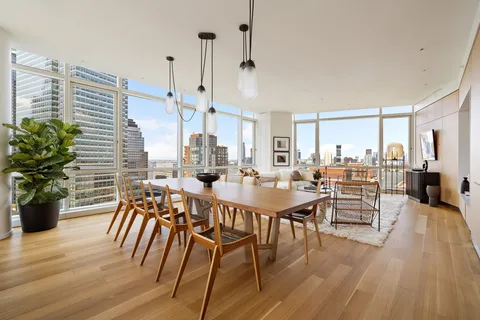 a view of a dining room and livingroom with furniture wooden floor a chandelier