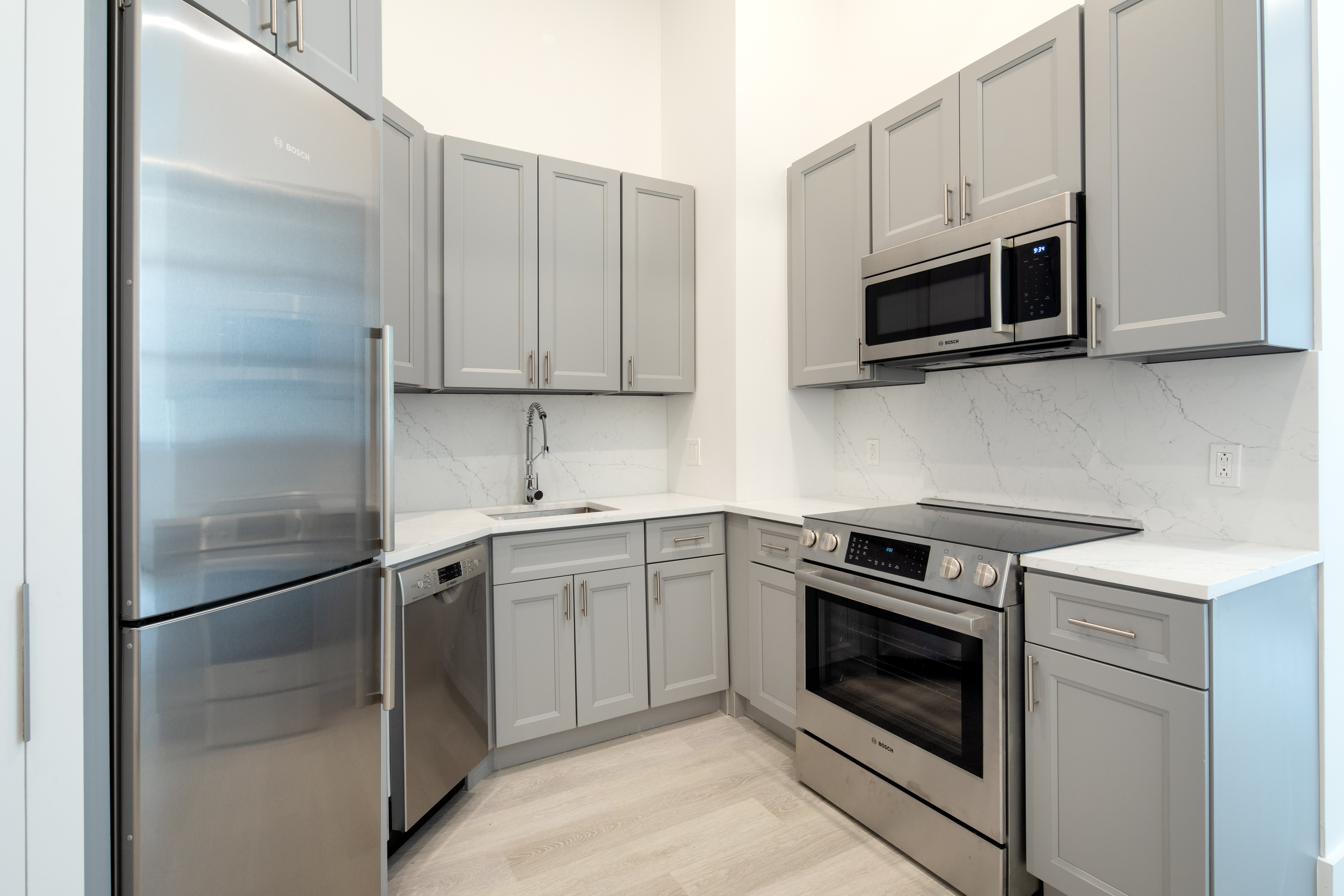 74 Leonard Street, Unit 3D Manhattan, NY 10013 - Photo 2 of 4 a kitchen with stainless steel appliances granite countertop white cabinets a microwave a sink and a refrigerator