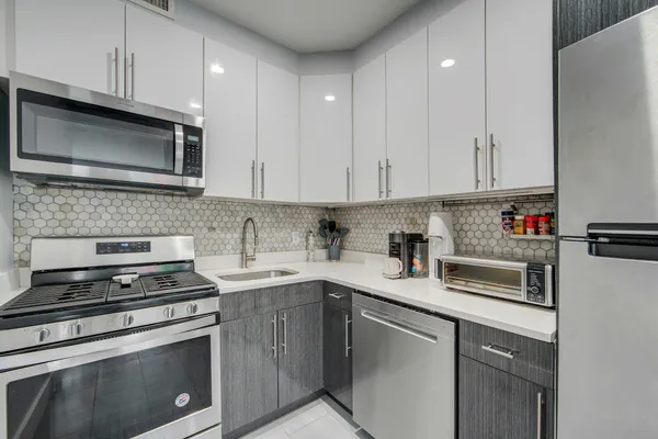 a kitchen with cabinets stainless steel appliances and sink