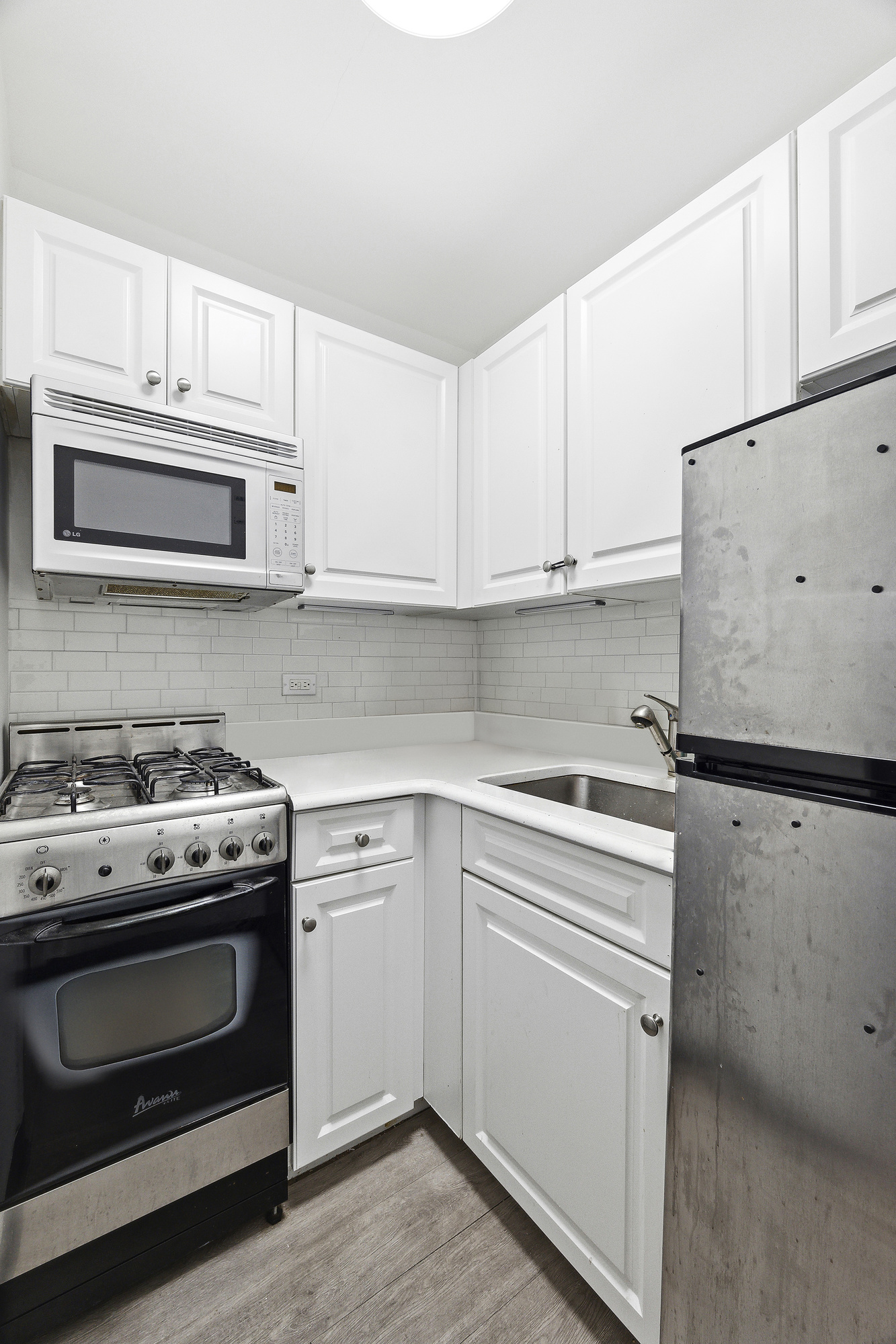 110 East 36th Street, Unit 5B Manhattan, NY 10016 - Photo 3 of 7 a kitchen with white cabinets and white appliances