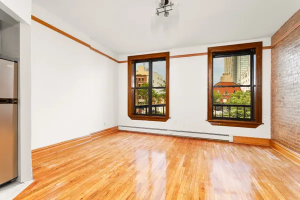 a view of an empty room with a window and wooden floor