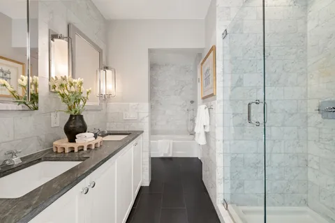 a bathroom with a double vanity sink a large mirror and a shower