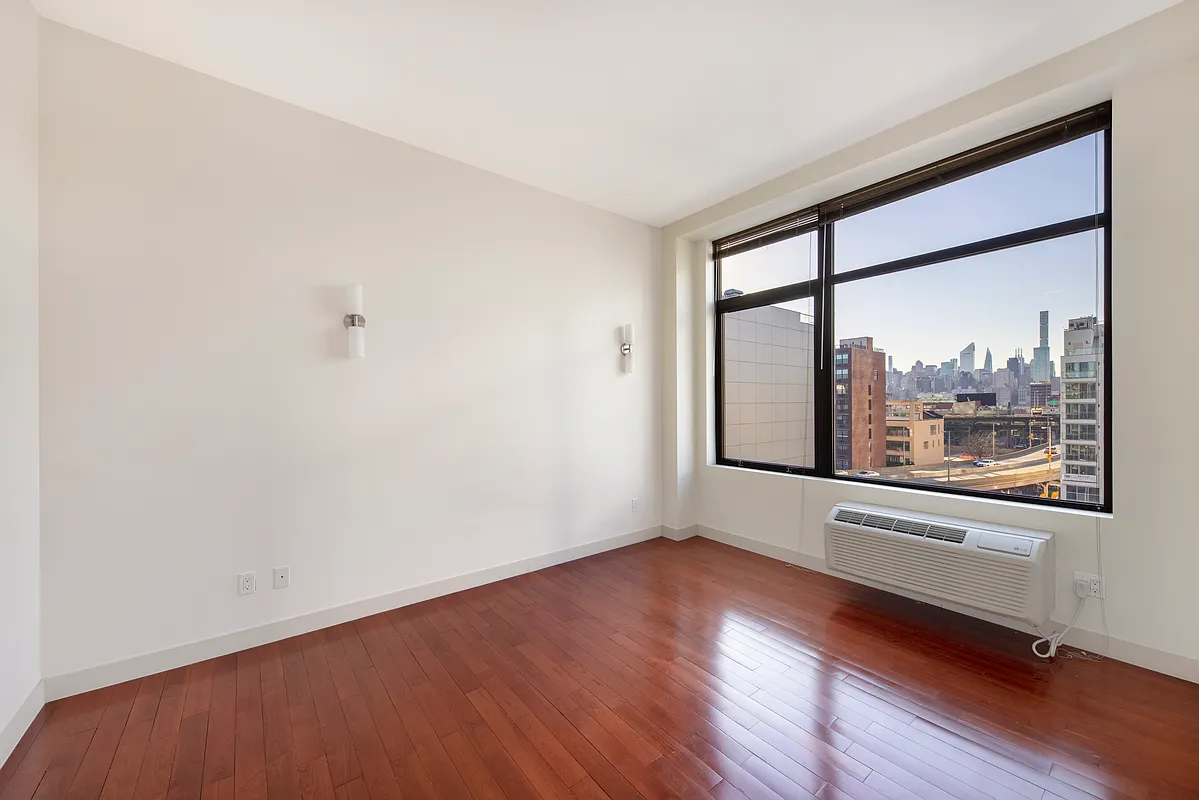 51-42 27th Street, Unit 6C Queens, NY 11101 - Photo 5 of 10 a view of a room with wooden floor and a window