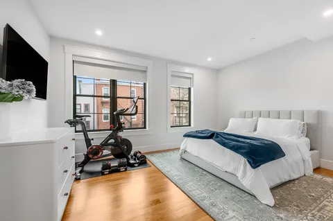 a bedroom with a bed a flat screen tv and a large window