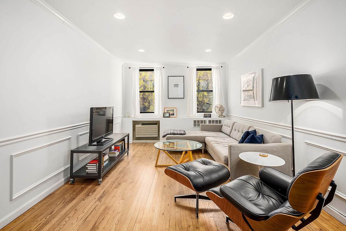 215 East 77th Street, Unit 4C Manhattan, NY 10075 - Photo 4 of 7 a living room with furniture a flat screen tv and a window