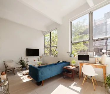 a living room with furniture a flat screen tv and a window